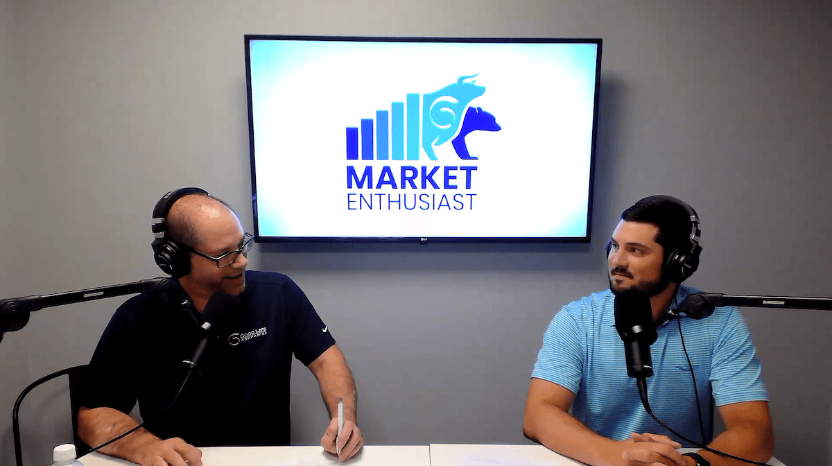 two men sit in front of a tv screen while recording a podcast